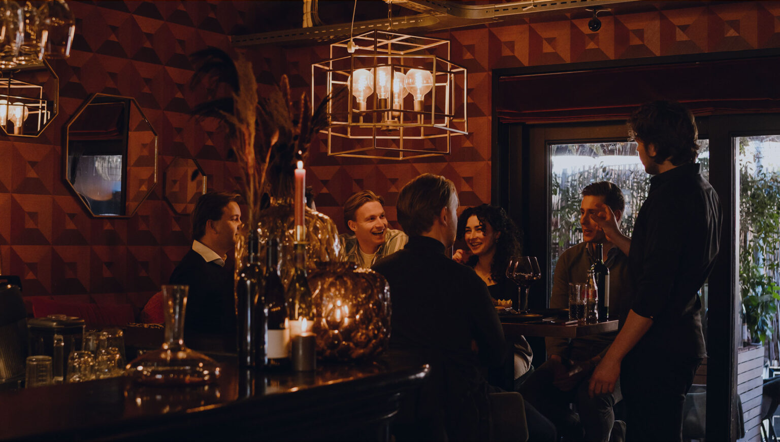 Gasten staan te borrelen met een glas in de hand in de wijnbar