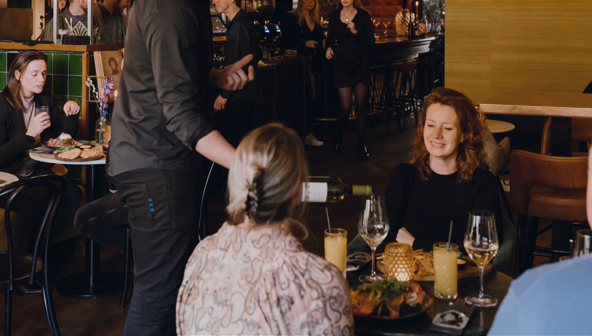 Gastheer schenkt wijn bij een gezelschap dat aan tafel zit te eten